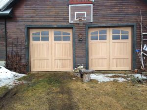 Two stamped wood-grain carriage house style doors on a dark brown home.